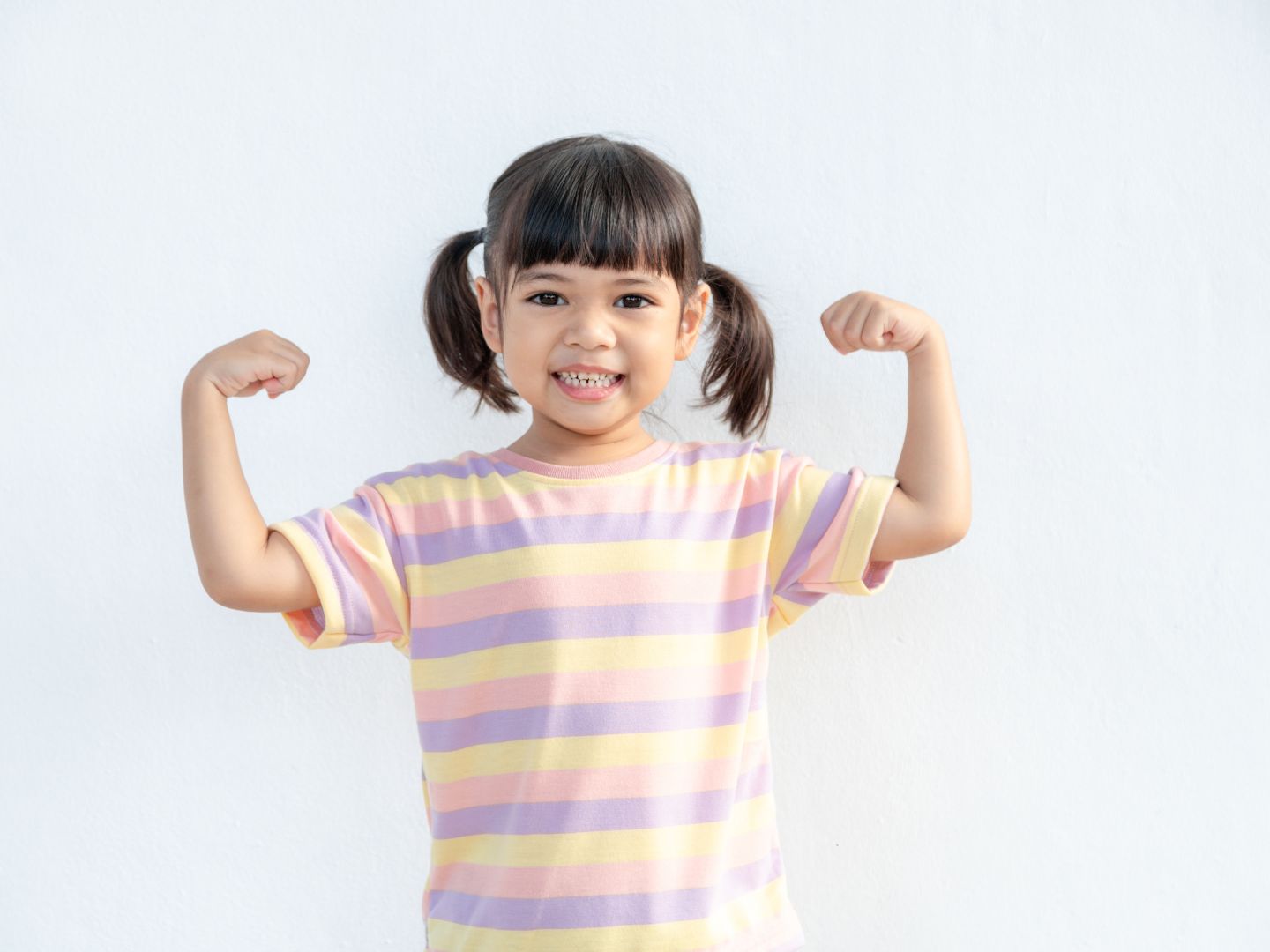 happy asian toddler showing her strong arms