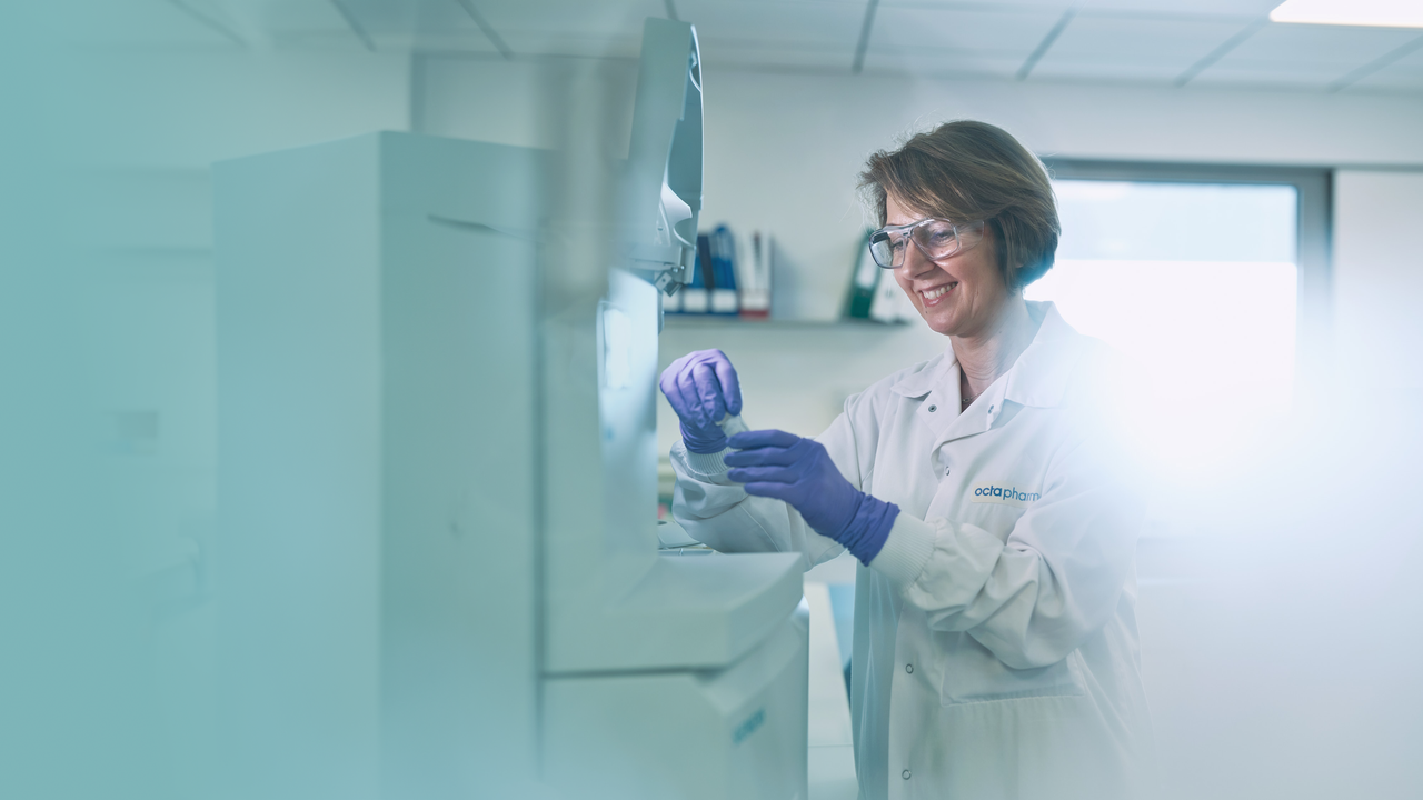 Une femme, qui travaille dans un laboratoire, porte une blouse et des lunettes de sécurité. Elle est en train de visser le bouchon un tuber à essai.