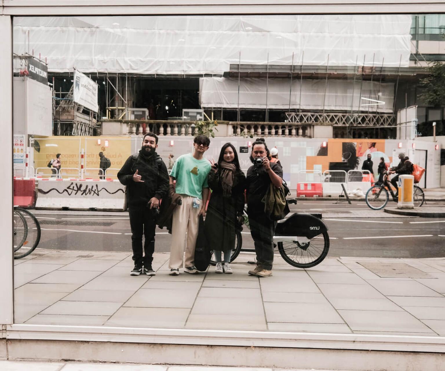 Four young adults posing together on a sidewalk in London in front of a construction site.
