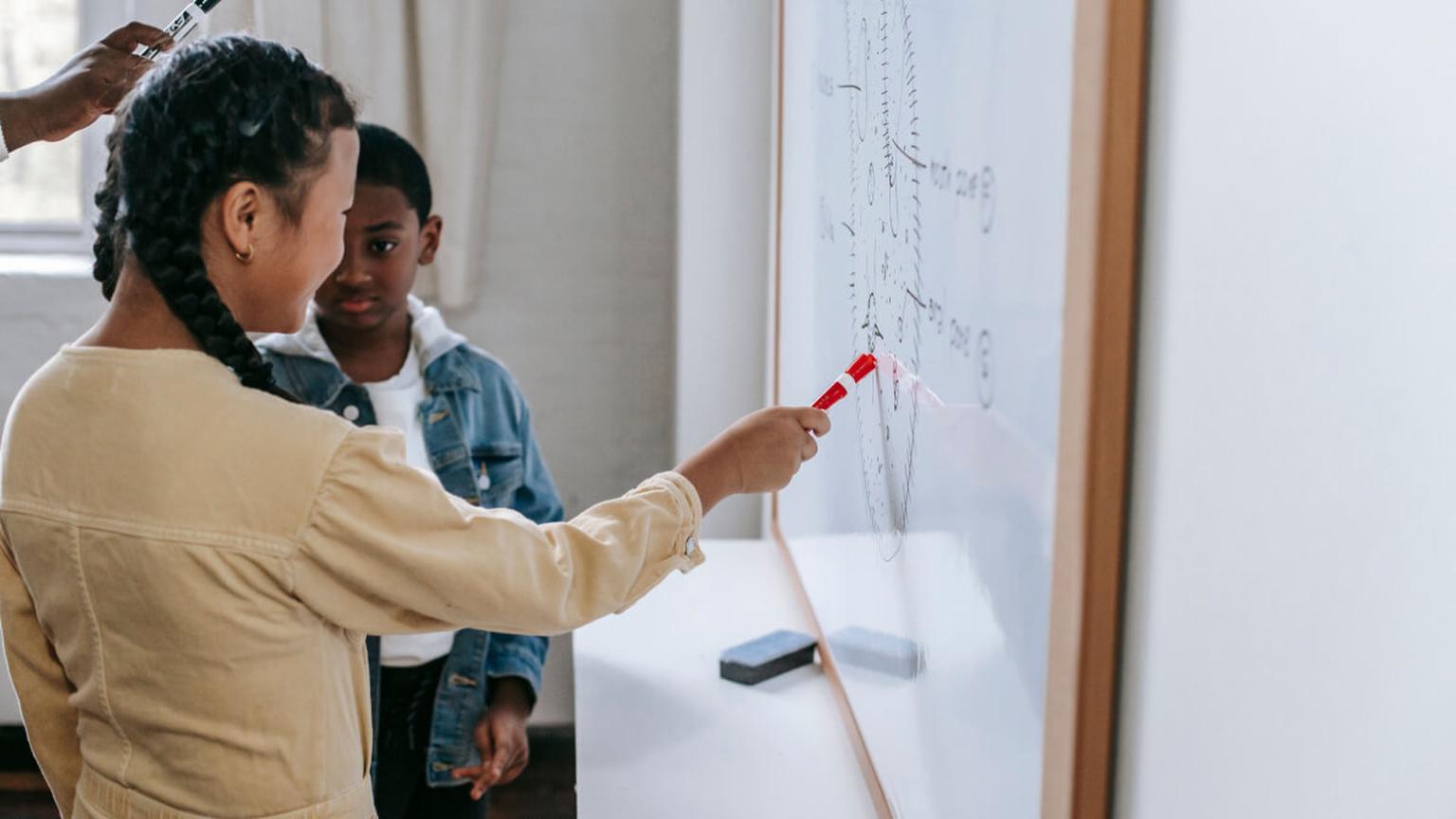 Two people discussing ideas at a whiteboard in an educational or professional setting.