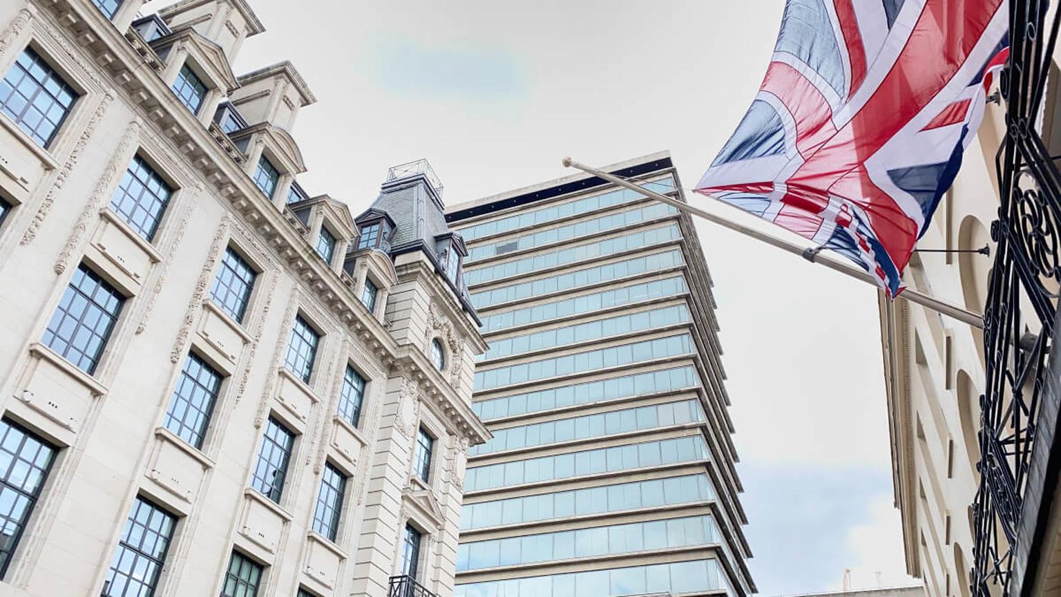 British flag flying outside historic buildings along a street in London.