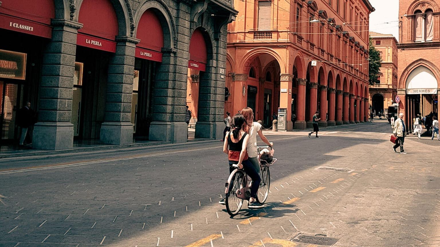 Radfahrer auf einer Straße mit historischen Arkadengängen in Bologna