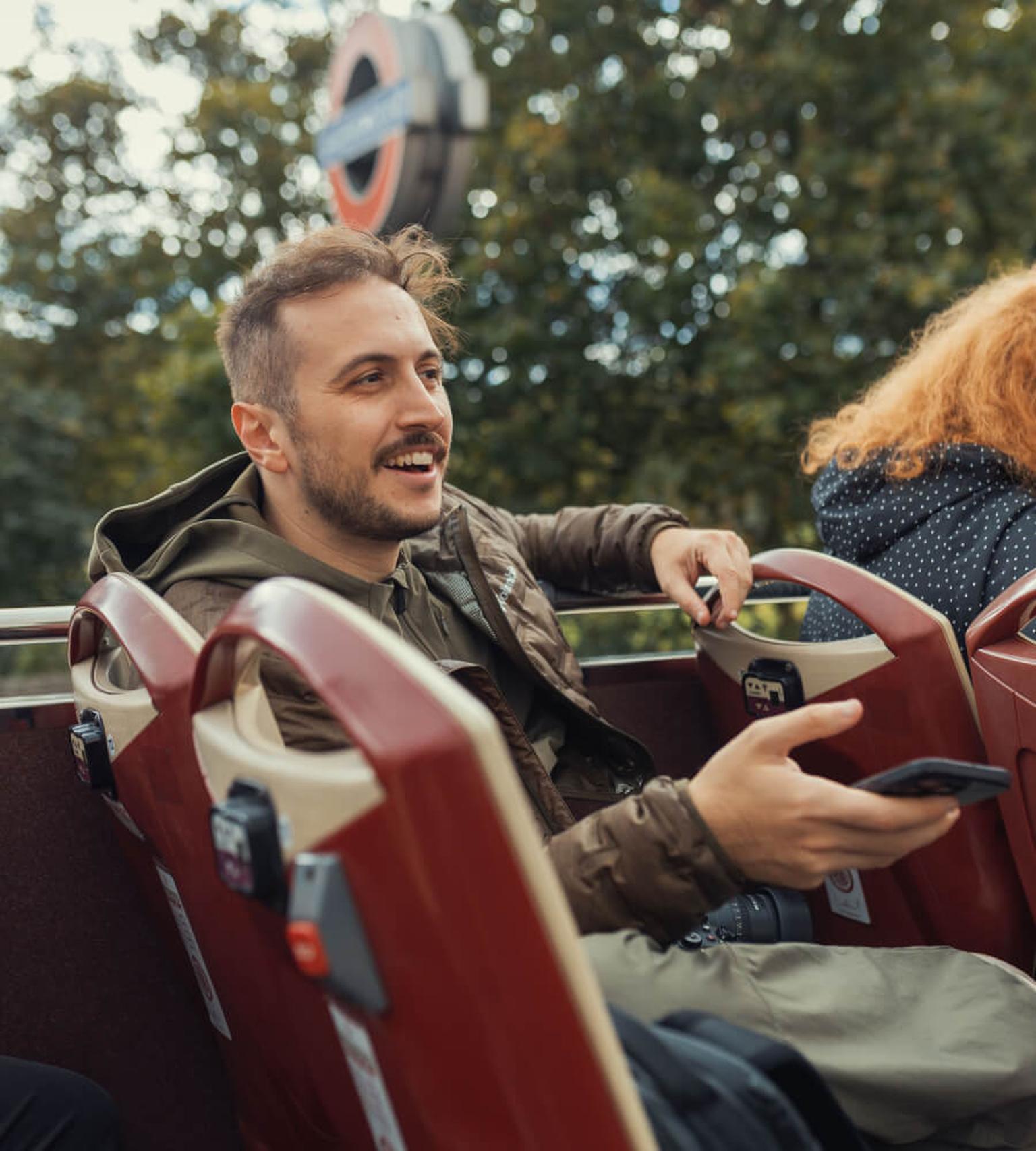 Young man enjoying a sightseeing tour on an open-top bus in London.