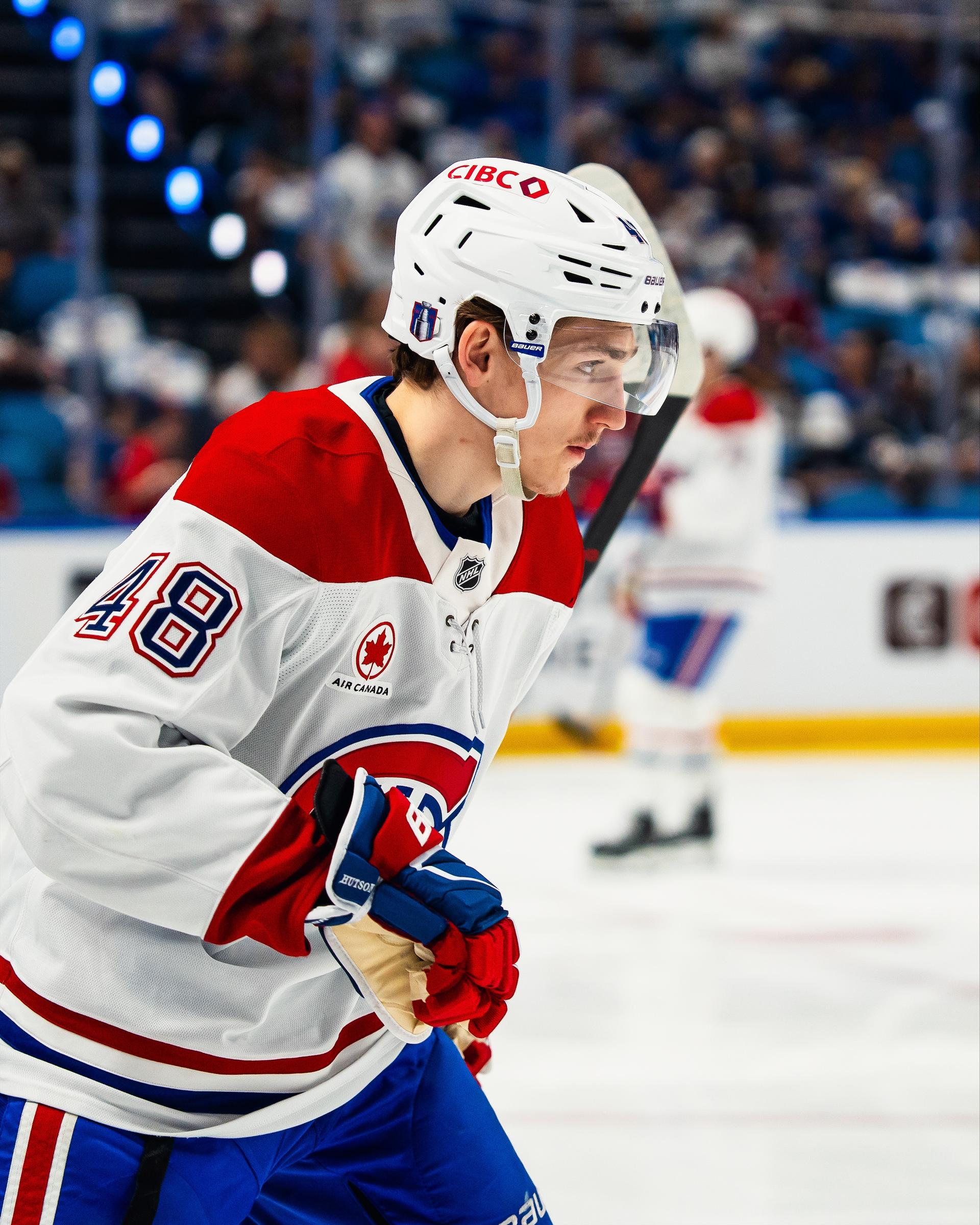 Lane Hutson in a white and red Canadiens jersey skating during warm-up.