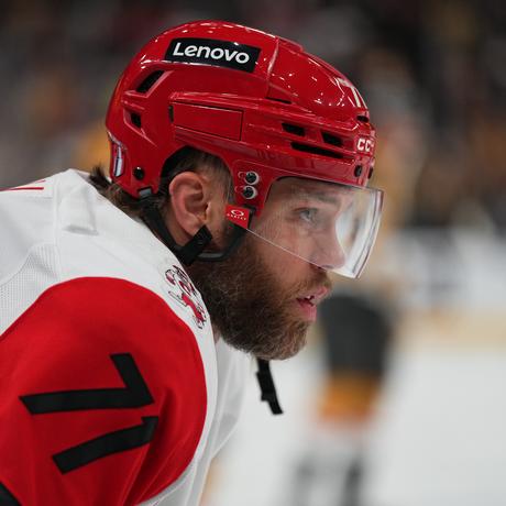 Taylor Hall, Hurricanes forward #71, leans forward in focused stance wearing white away jersey.