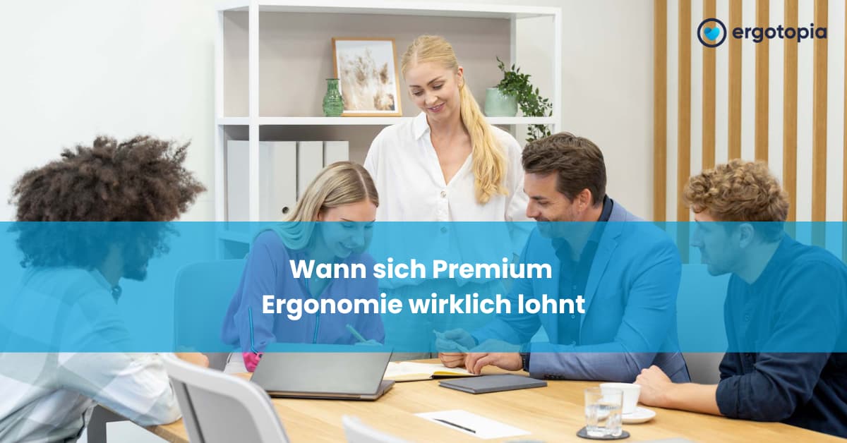 Fünf Kollegen arbeiten gemeinsam am Konferenztisch mit Laptop in freundlichem modernem Büro.