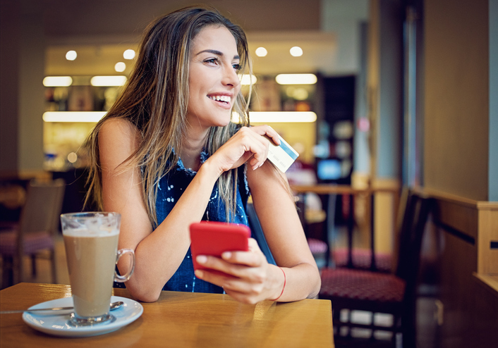 Girl is sitting in a cafe, and shopping online using her credit card