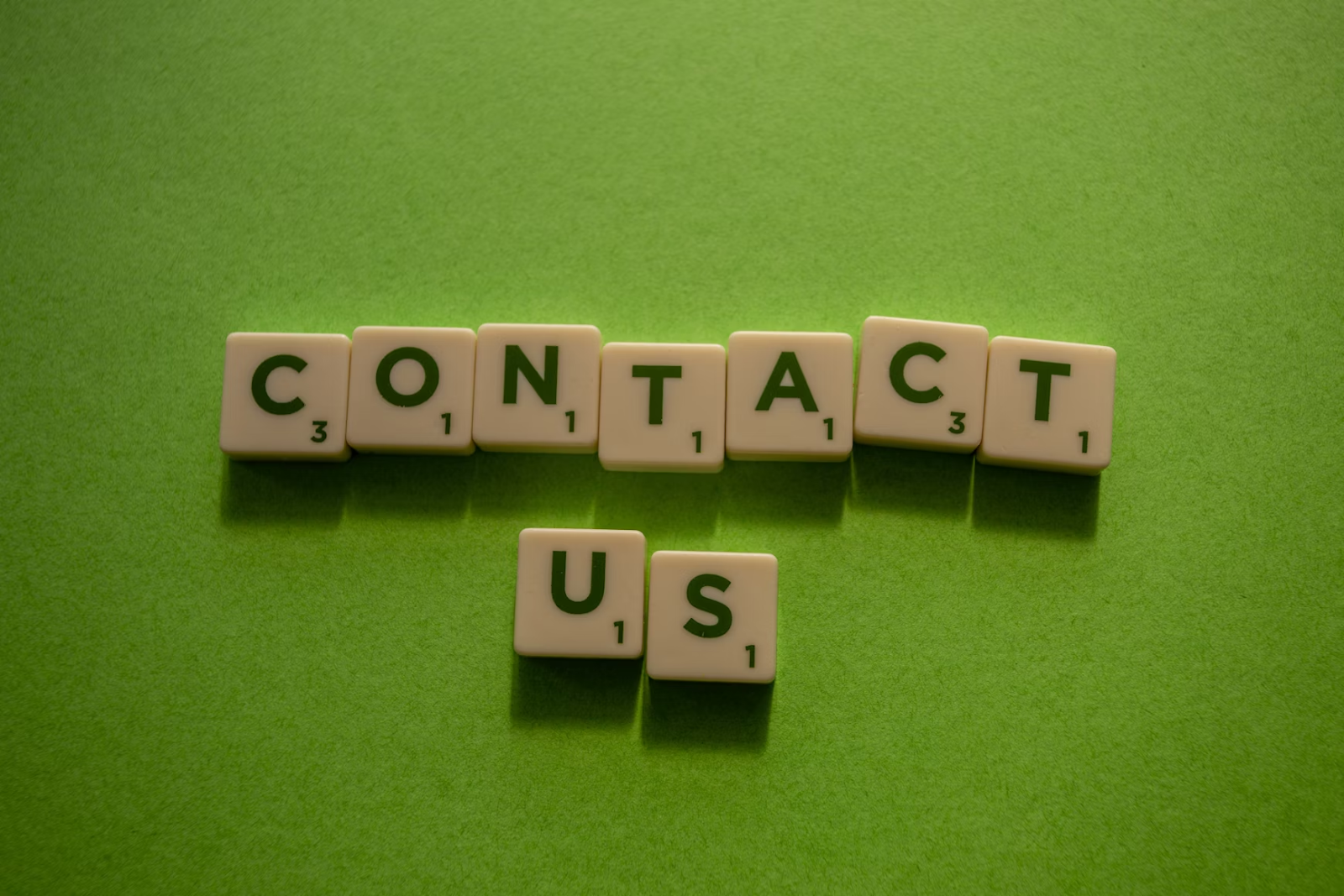 dices with letters that say "contact us" on green textile