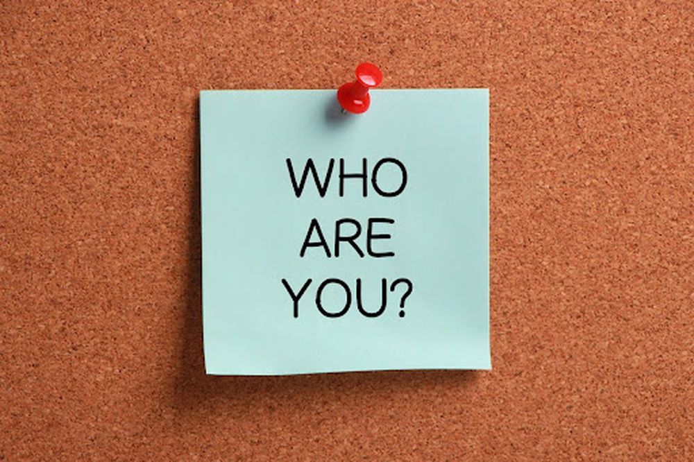 Sticky note with the words “Who are you?” pinned to a corkboard, symbolizing the importance of brand identity when building referral networks.