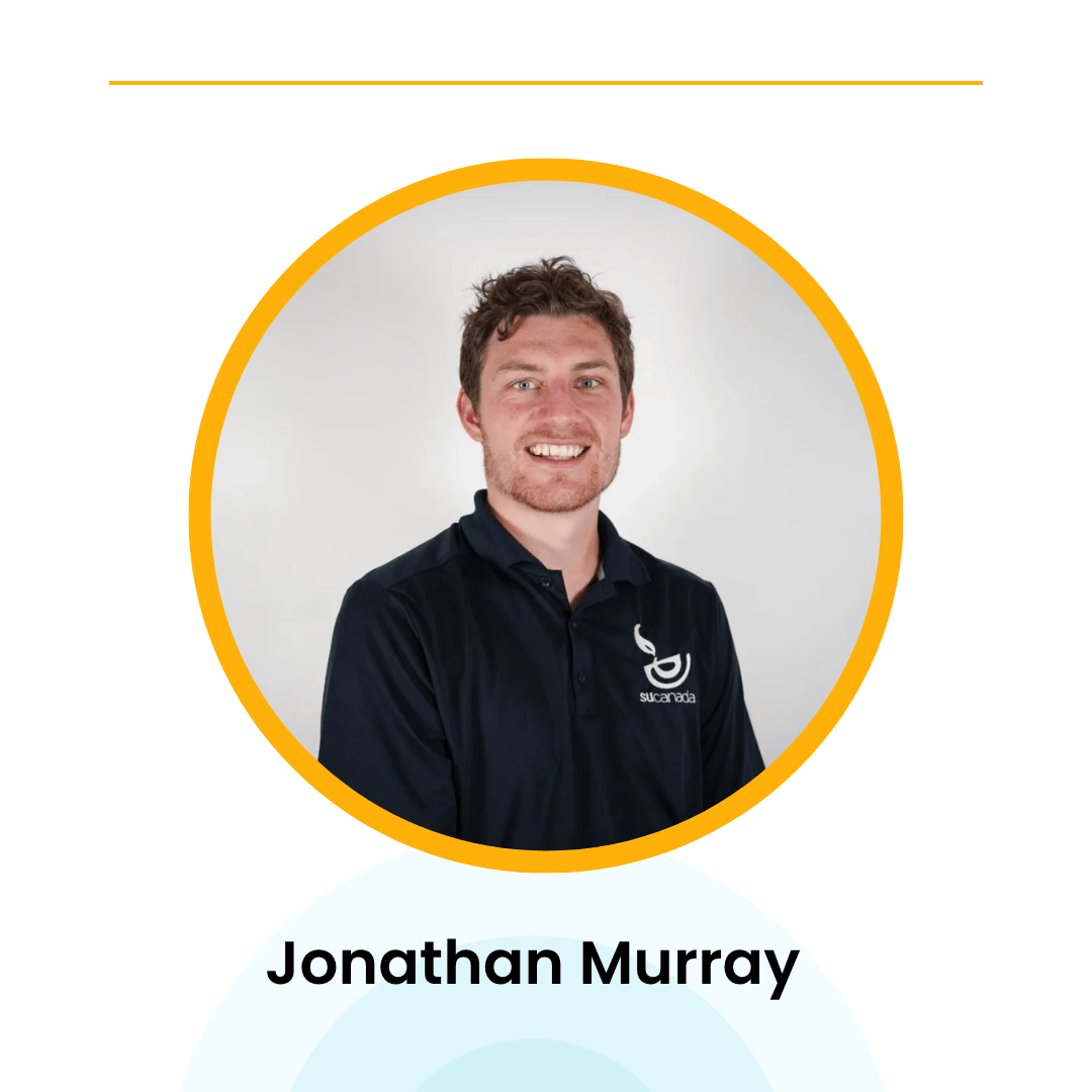 A man in a navy shirt with a logo, smiling against a gray background inside an orange-bordered circle.