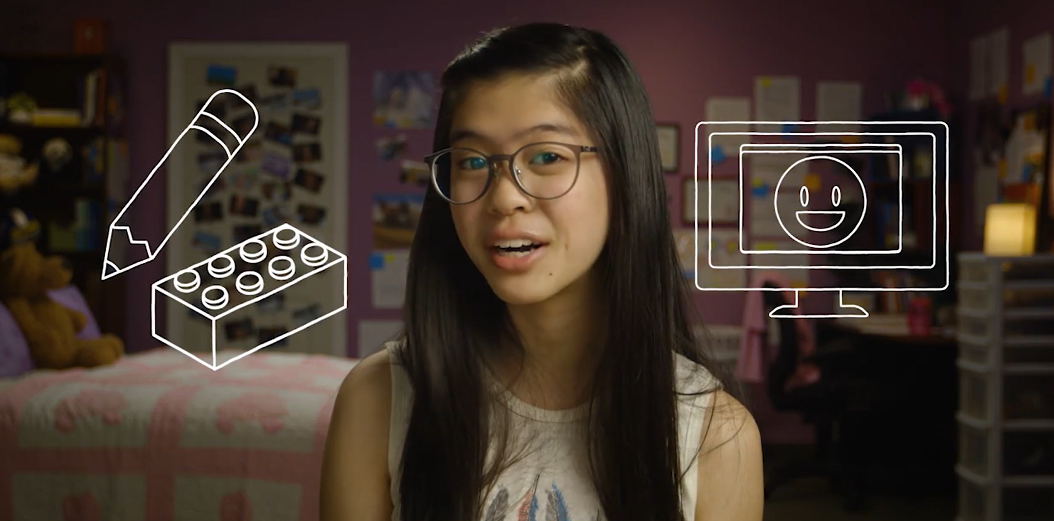 A young woman with long hair and glasses smiles in a bedroom with drawn icons of a pencil, Lego brick, and computer screen around her.