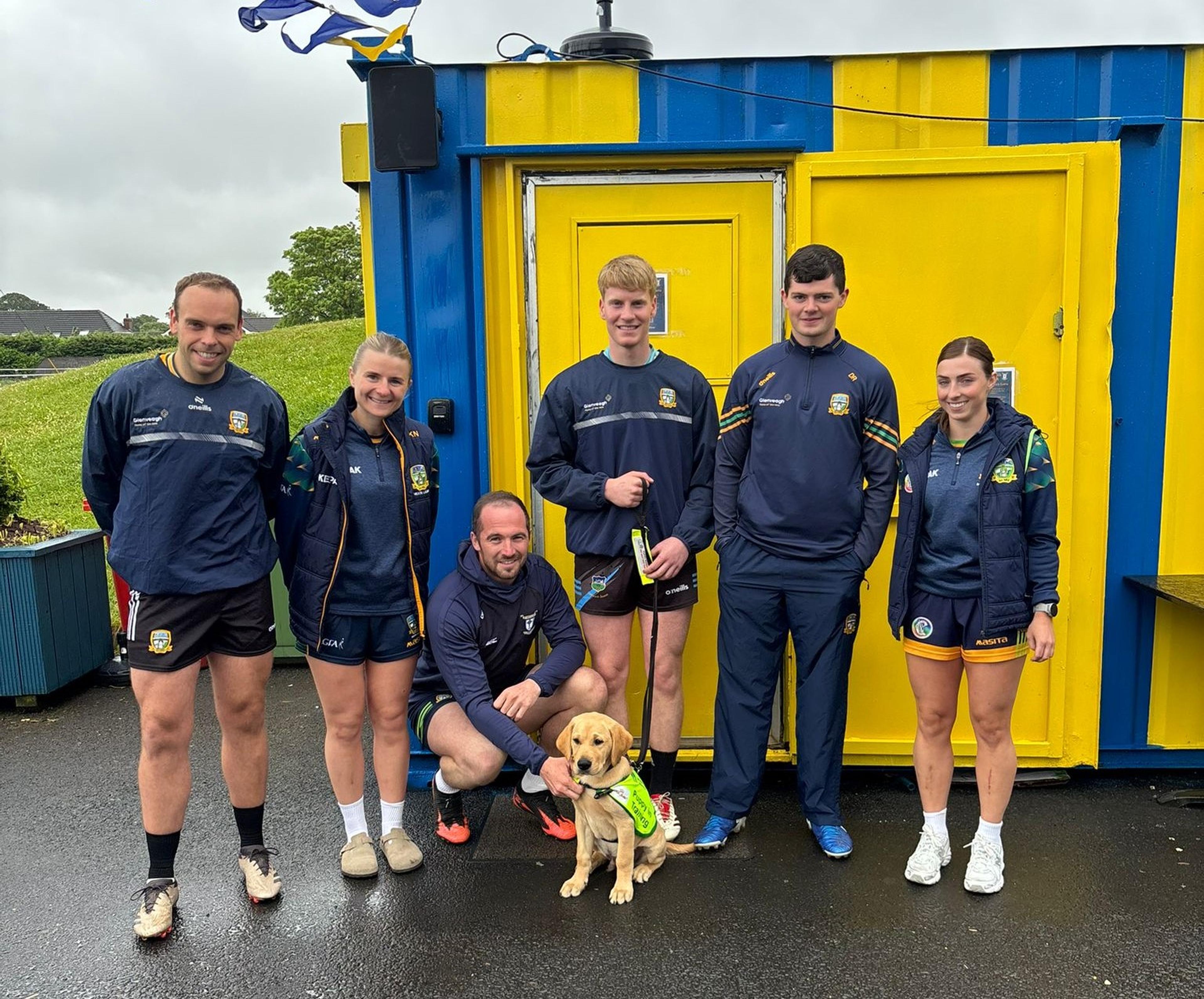 Paw-dí standing with GAA players outdoors