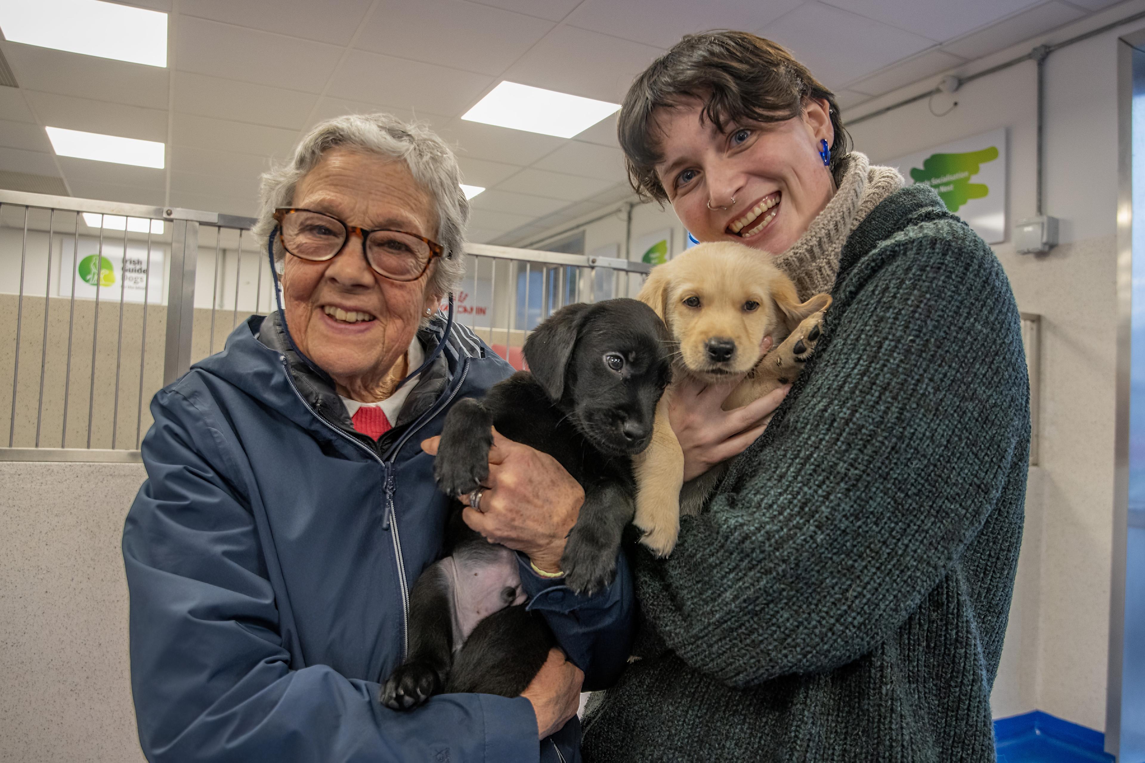 Emma and friend pictured holding two puppies