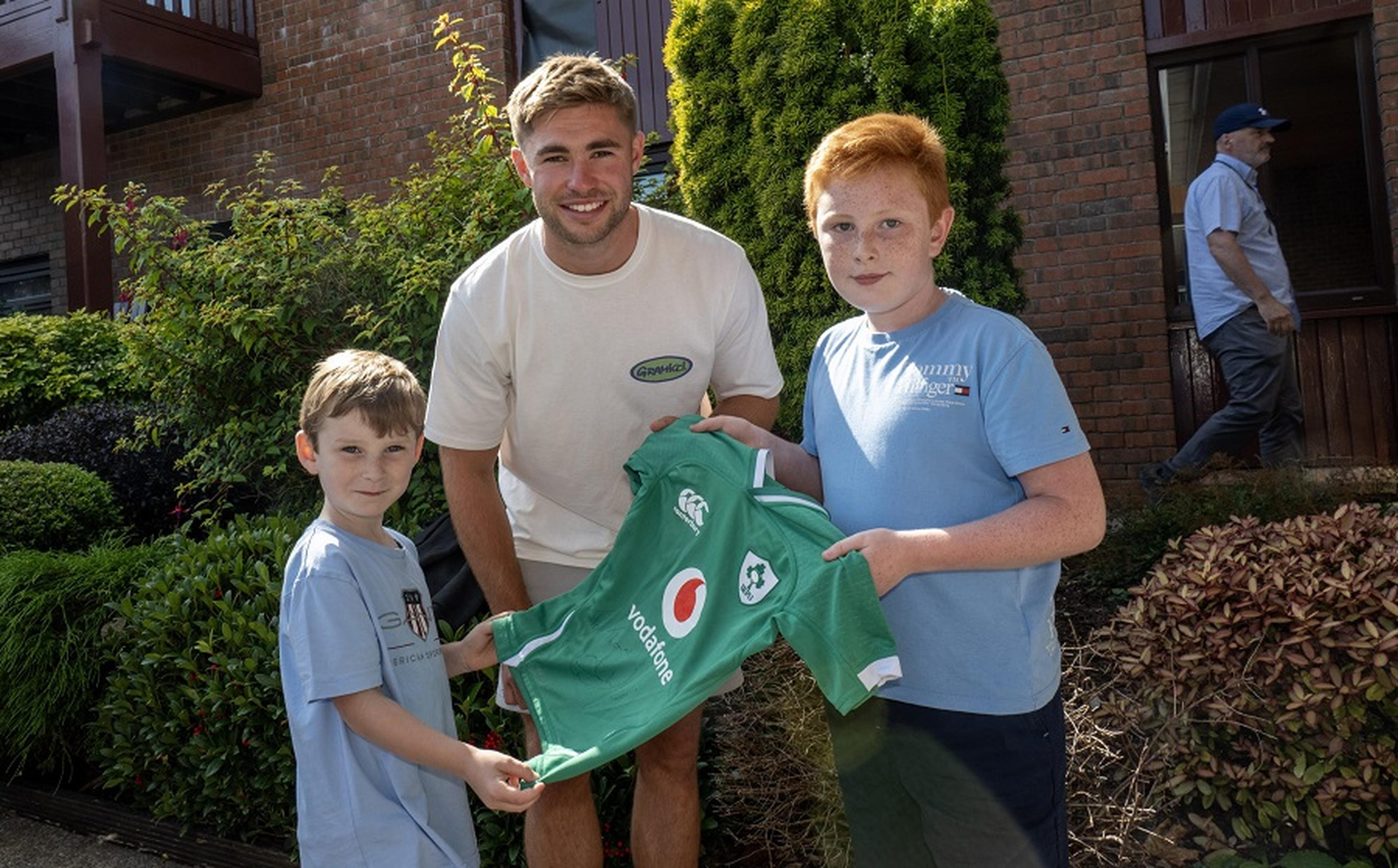 Jack Crowley standing with two boys who are holding a jersey at the 2024 Open Day