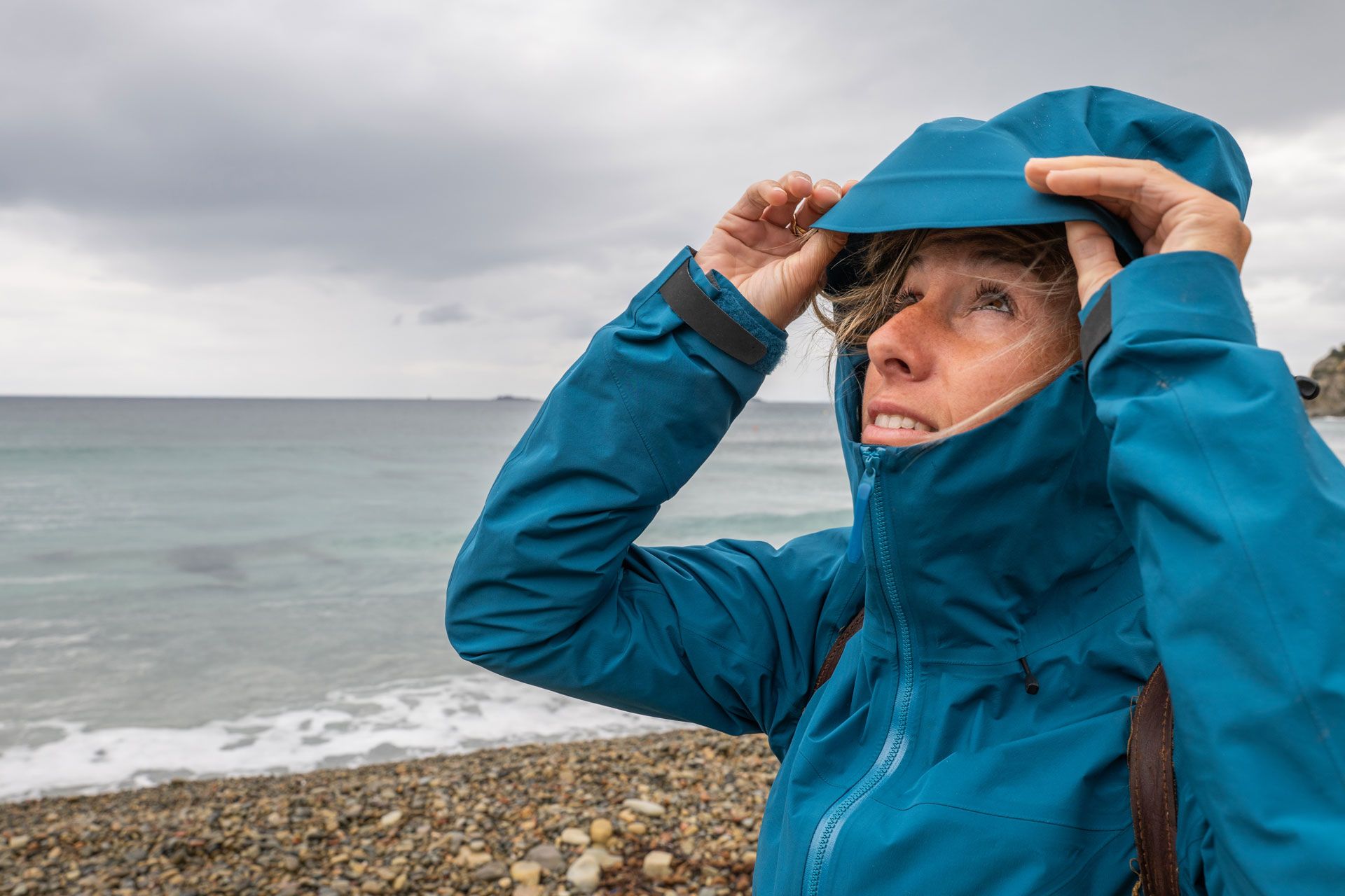 Junge Dame am Strand schaut auf bewölktem Himmel