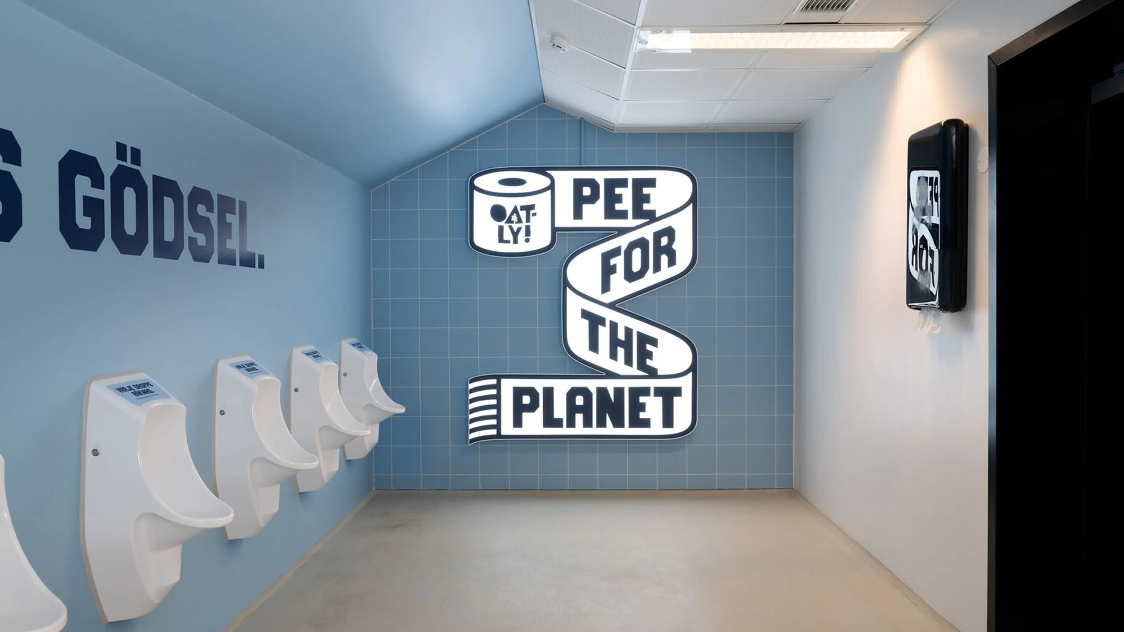 Blue restroom with urinals and a wall sign reading "Pee for the Planet" by Oatly, promoting an environmental message.