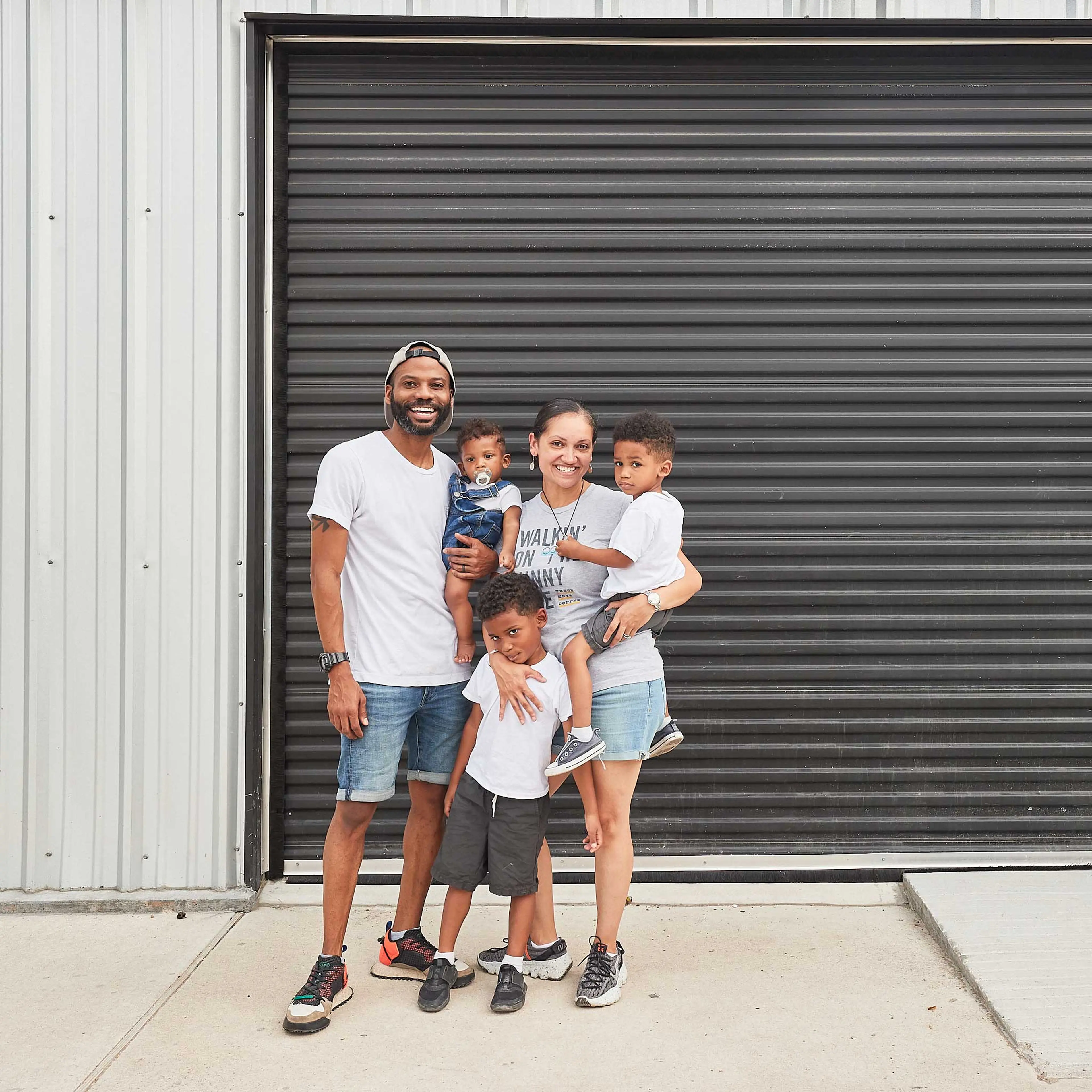 Family with three kids standing in front of a building