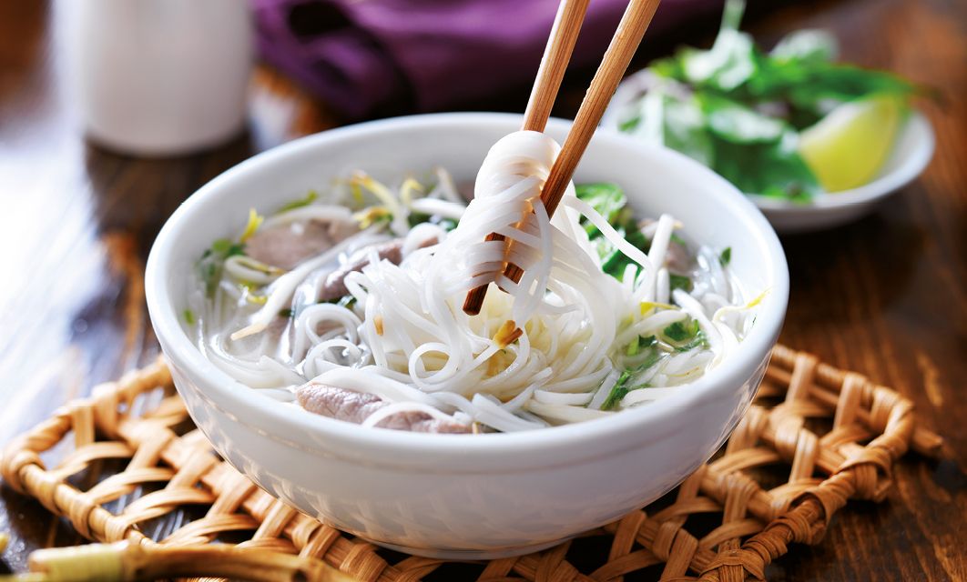 picking up noodles out of a bowl of pho