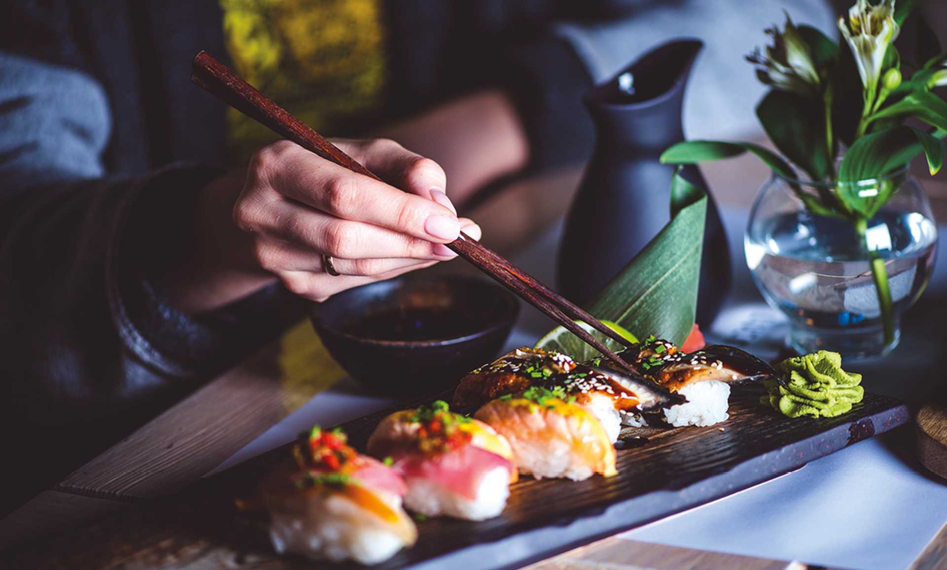 Man eating sushi set with chopsticks on restaurant