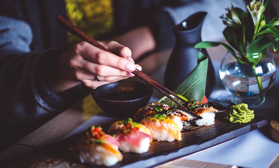 Man eating sushi set with chopsticks on restaurant