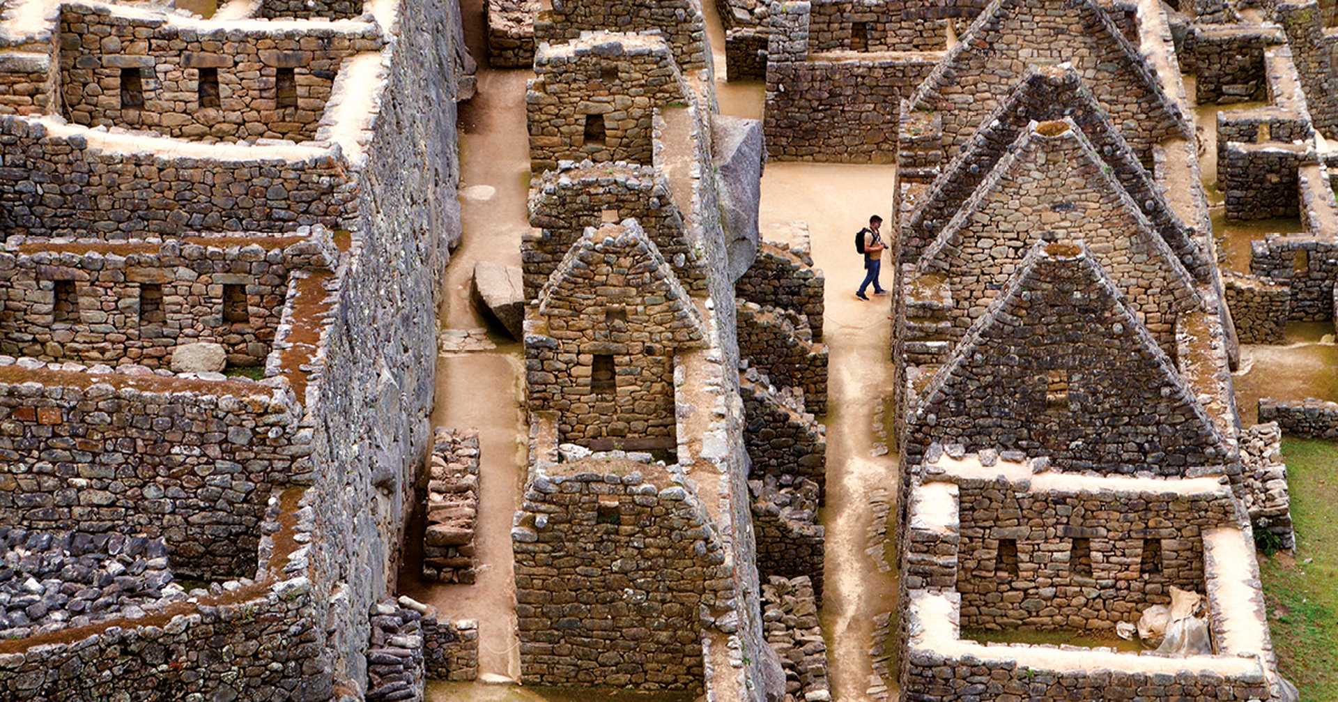 A man wanders through the ruins of the ancient Incan city of Machu Picchu in Peru