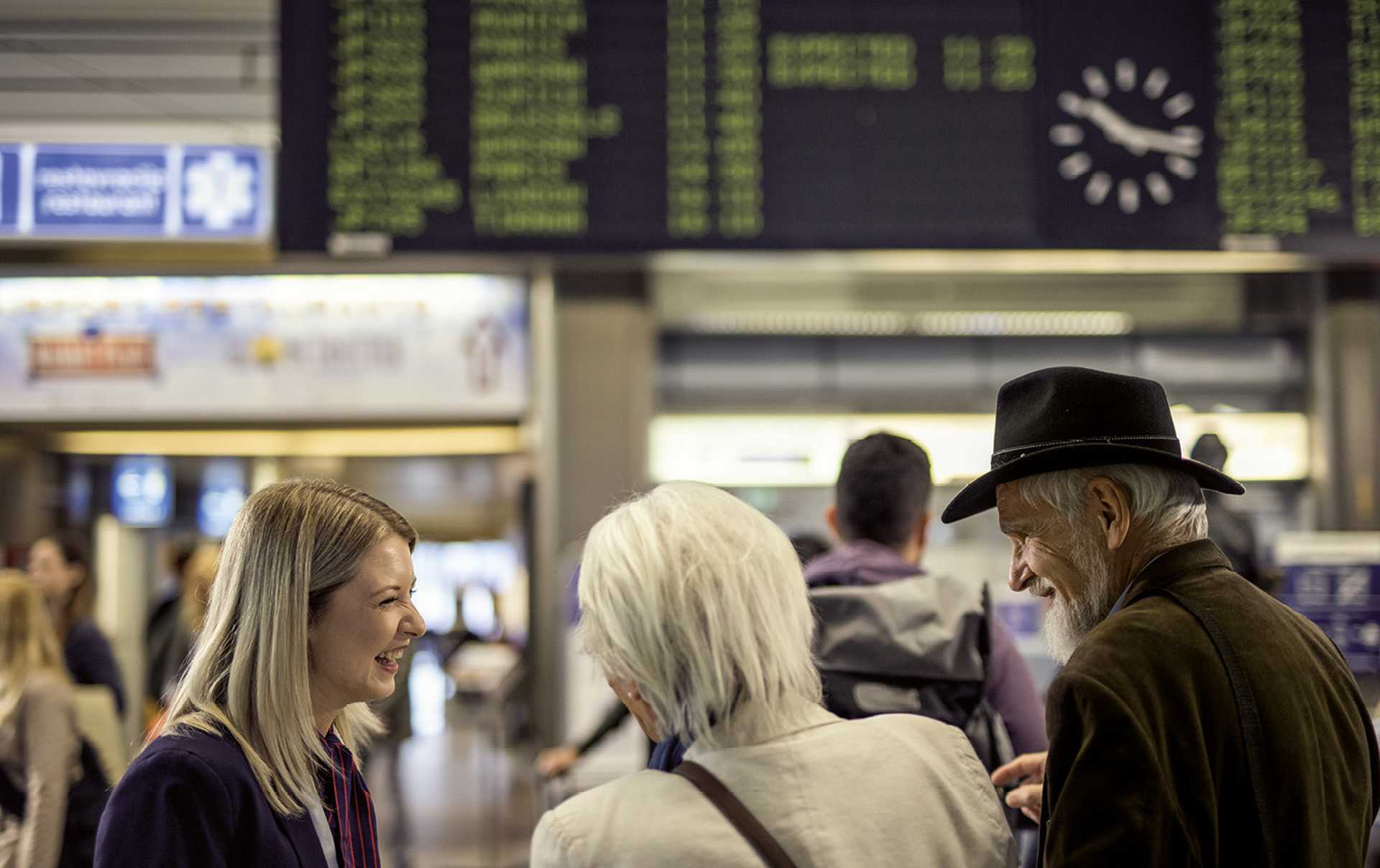 Smiling airport attendant helping elderly couple