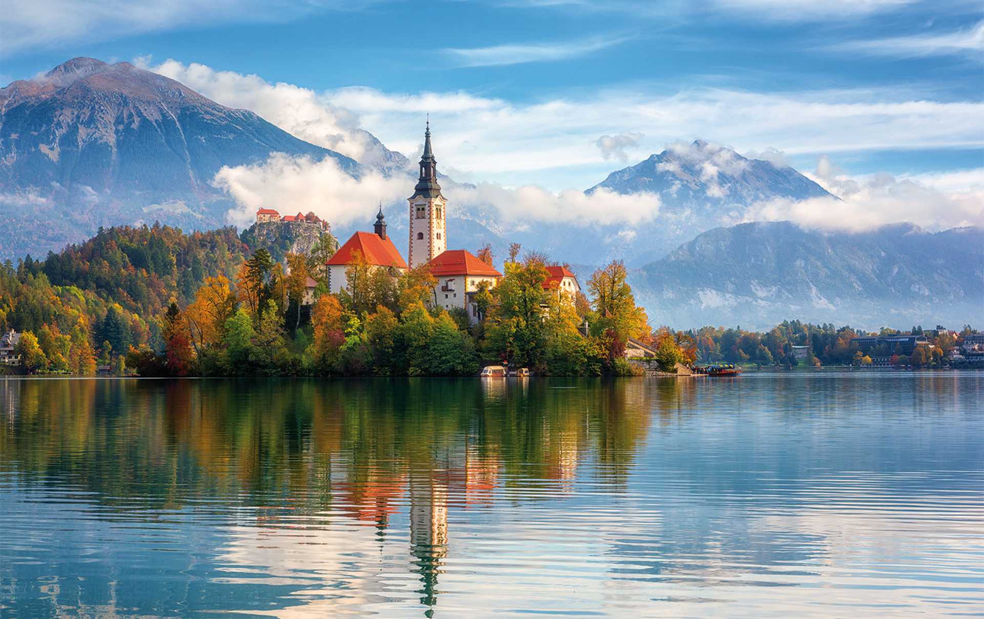 Famous alpine Bled lake (Blejsko jezero) in Slovenia, amazing autumn landscape. Scenic view of the lake, island with church, Bled castle, mountains and blue sky with clouds, outdoor travel background