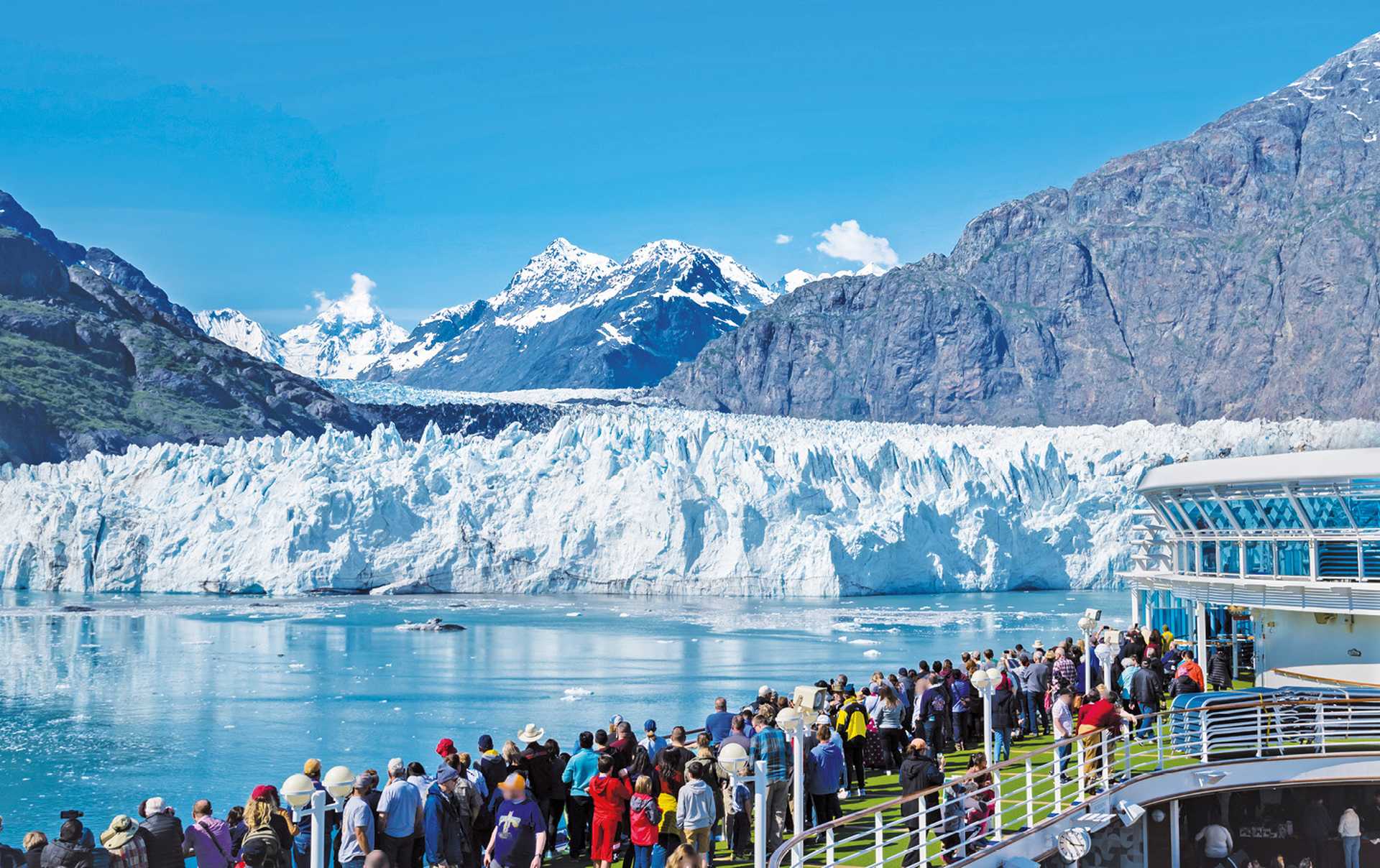 A group of tourists are enjoying the gorgeous view of the Margerie Glacier in the Glacier Bay of Alaska on a sunny day. 