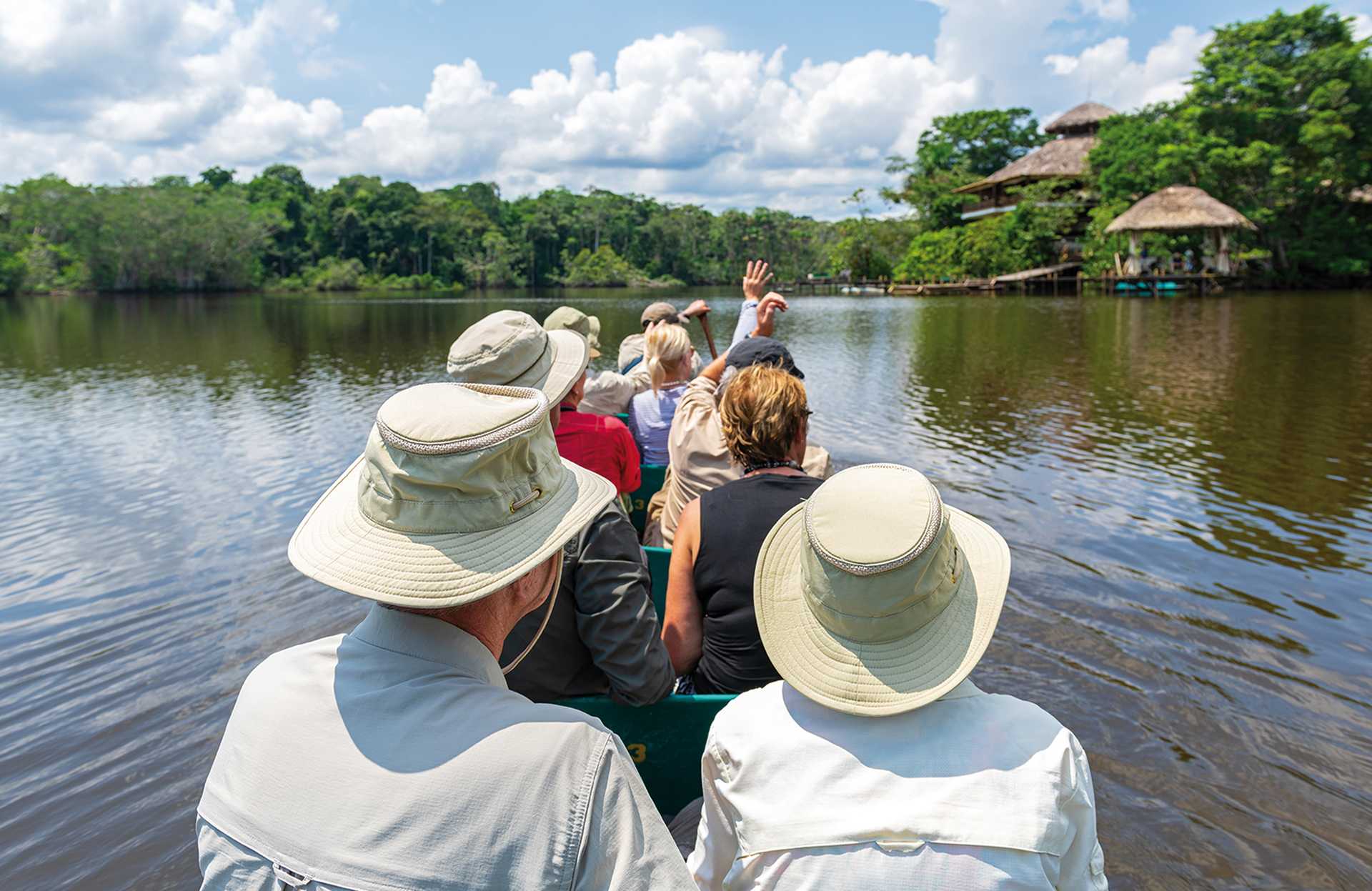 Tourist group arriving at Amazon rainforest lodge by canoe, Yasuni national park, Ecuador.