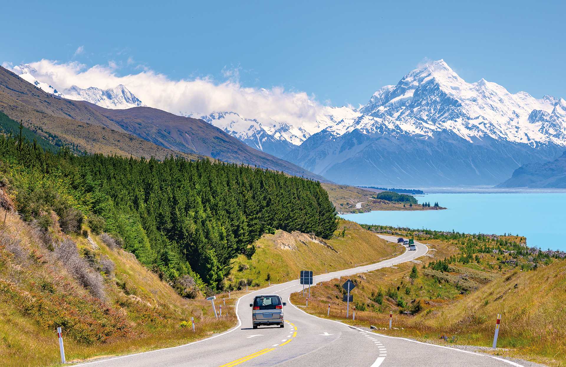 The road curves along Lake Pukaki and Mount Cook on a clear day at Peter's Lookout in the South Island of New Zealand.