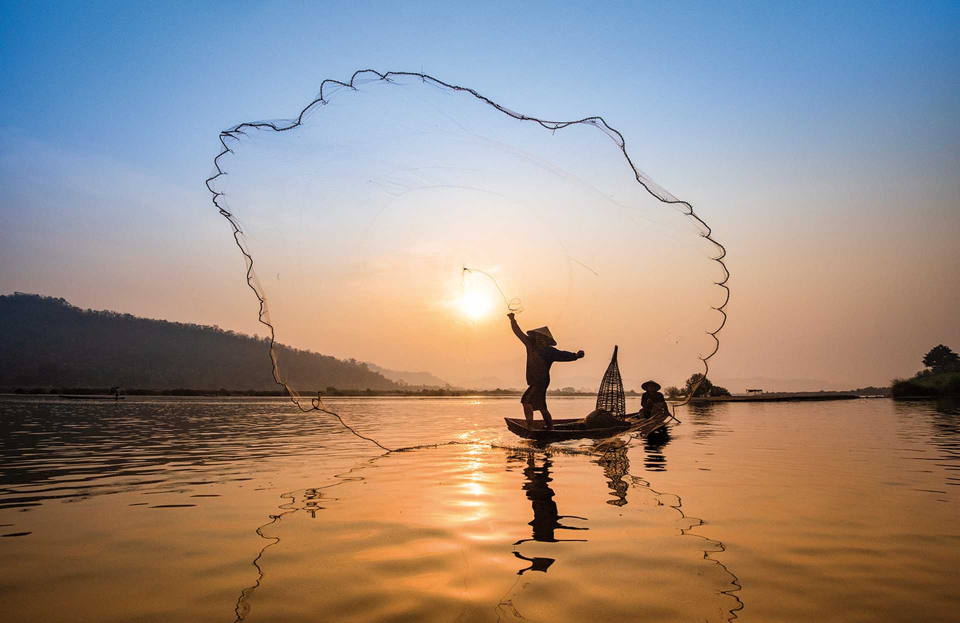 Asia fisherman net using on wooden boat casting net sunset or sunrise in the Mekong river 