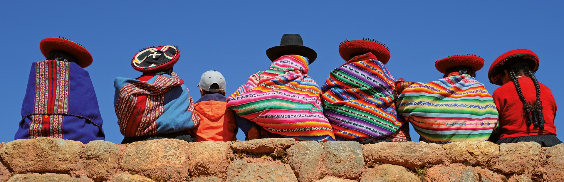 Quechua ladies and a young boy chatting on an ancient Inca wall, Cusco Province, Peru