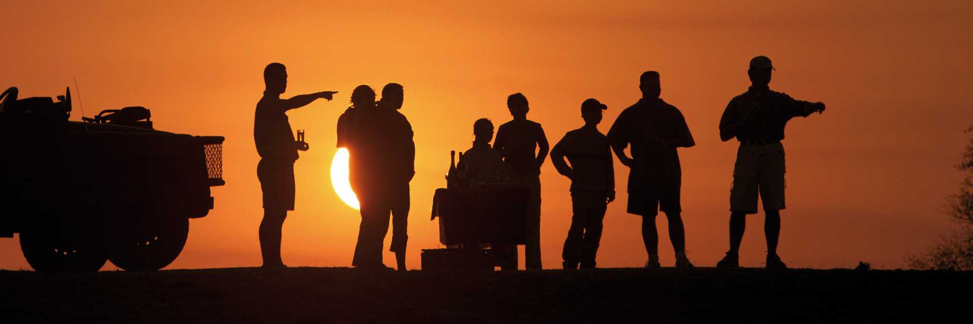 On game drive in South Africa, guests enjoy snacks and drinks at sunset.