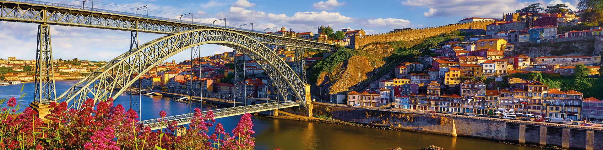 Porto, Portugal. Evening sunset picturesque view at old town with antique houses and red roofs near bridge Ponte de Dom Luis on river Douro.