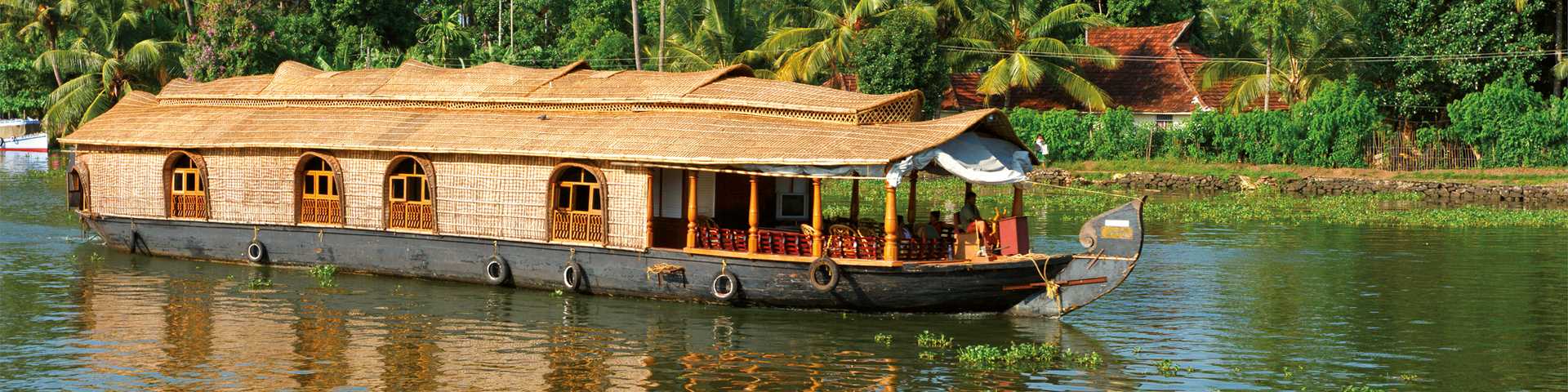 Originally called Kettuvallams (in the Malayalam language, Kettu means ‘tied with ropes’, and vallam means ‘boat’), these boats were once used to carry rice and spices to Kochi’s port. Now, they more often sail the waters on and around Lake Vembanad, known as the ‘Venice of the East’ for its palm-fringed canals and backwaters.
Traditional methods are used in their construction: the hull is made of aanjili wooden planks, held together by ropes of coconut fibre, while bamboo poles and palm leaves make up the roof. The exterior of the boat is painted with protective coats of cashew nut oil. 
A lounge and deck area is set up with cushioned chairs for taking in the views as you gently glide through the water. 
