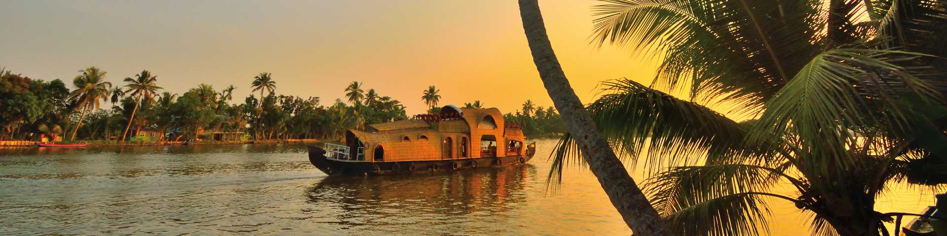 A houseboat sailing in Kerala backwaters during sunset, India