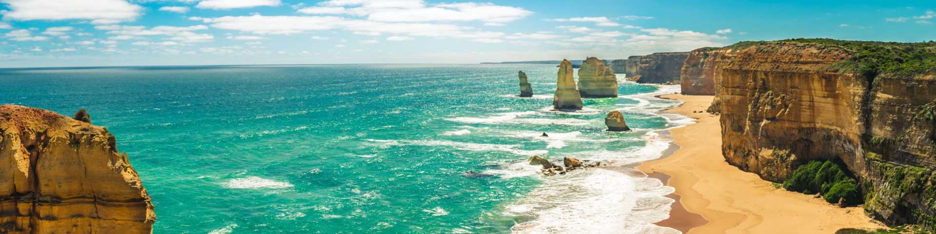 Australian beach with blue sea and golden sand with cliffs