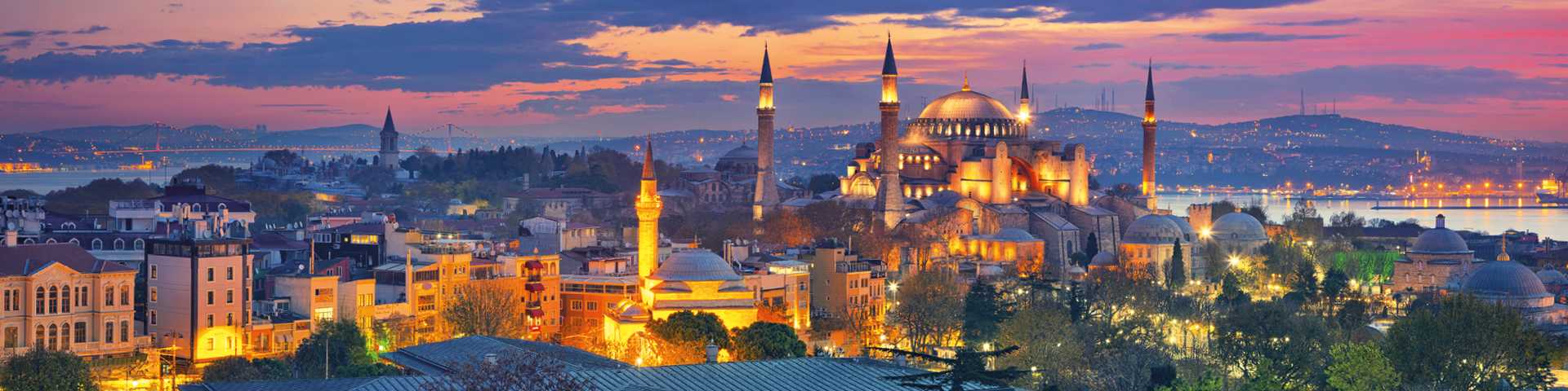 Panoramic view over Istanbul lit up at night against a sunset sky, Turkey