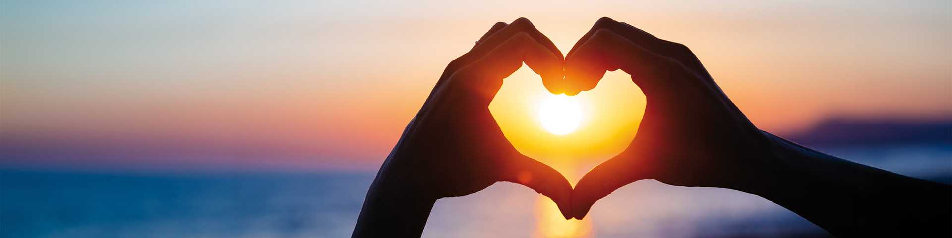 Hand heart around sunrise