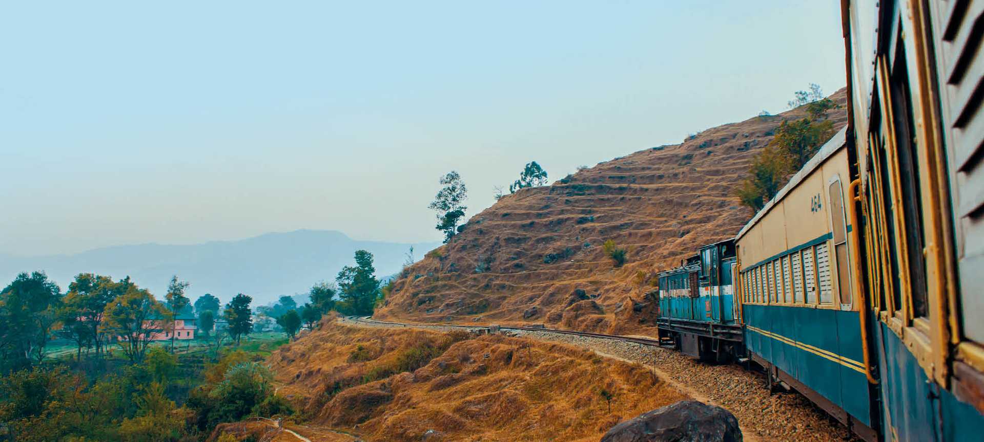 A narrow-gauge toy train travels through the countryside in India