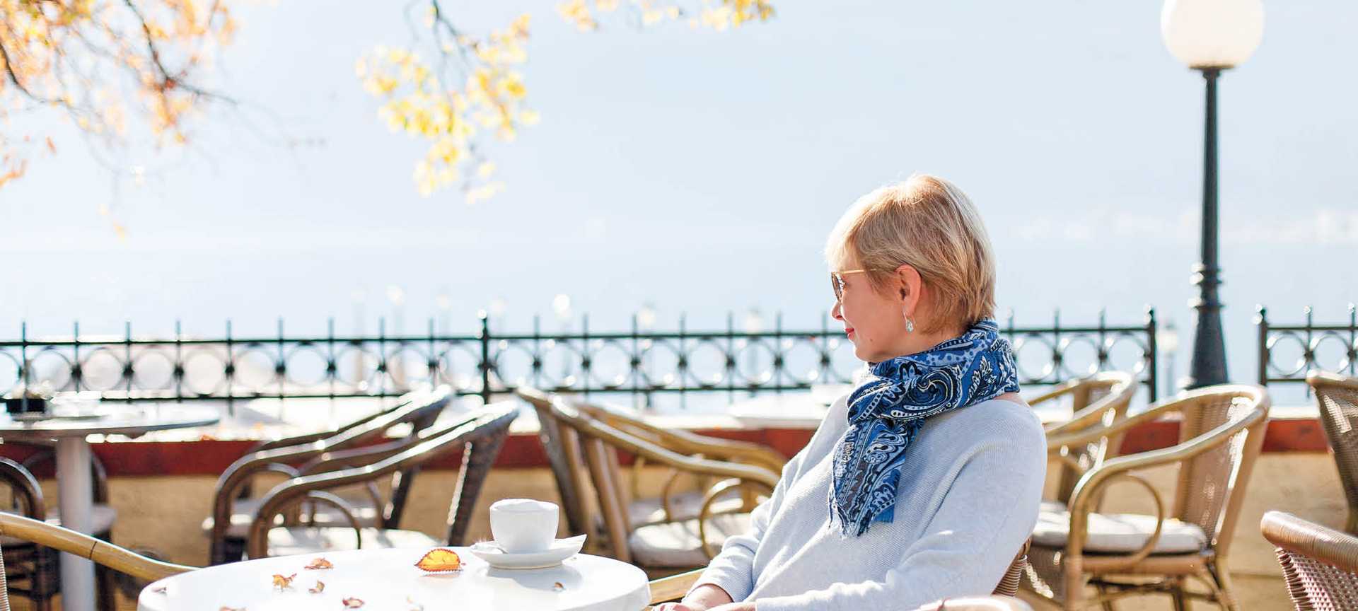 A lady sits at a cafe with a cup of coffee