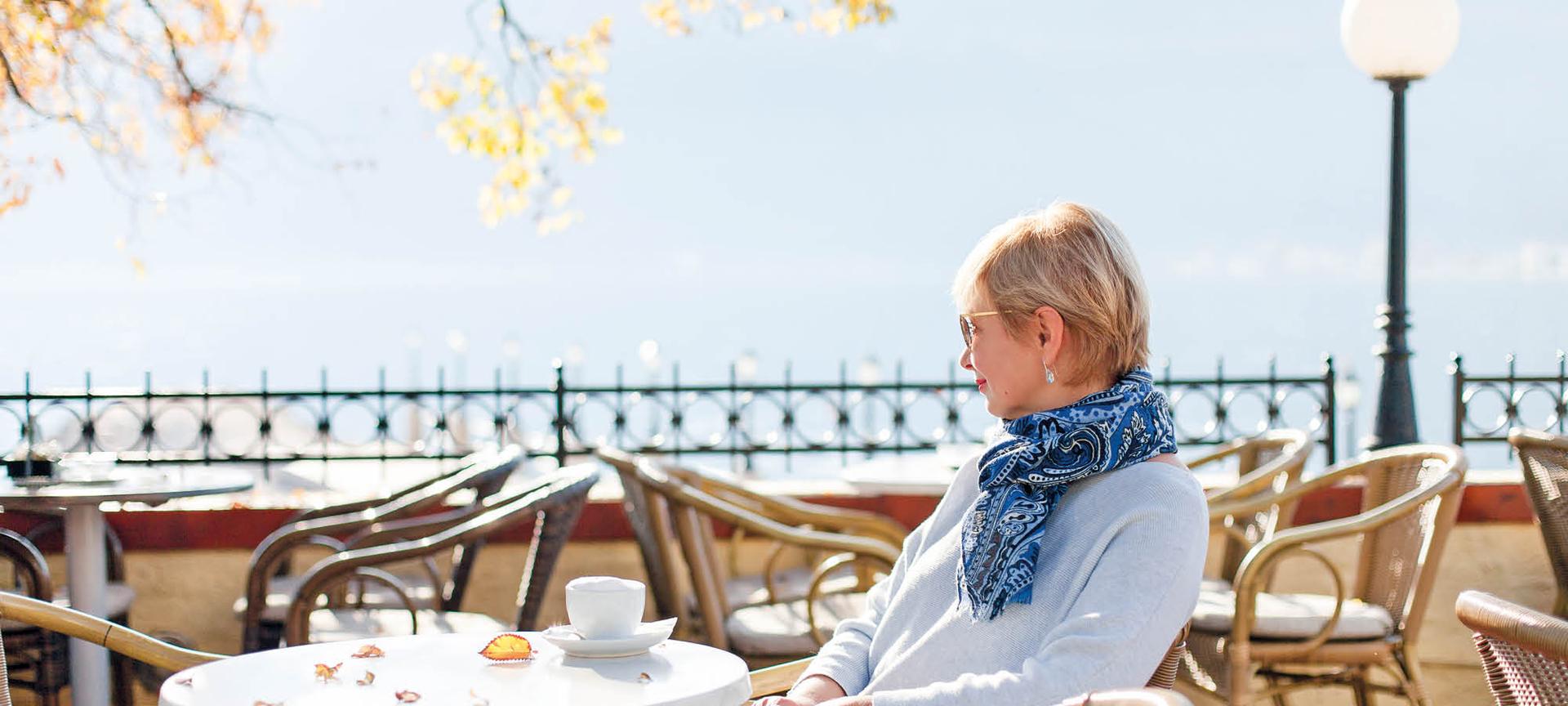 A lady sits at a cafe with a cup of coffee