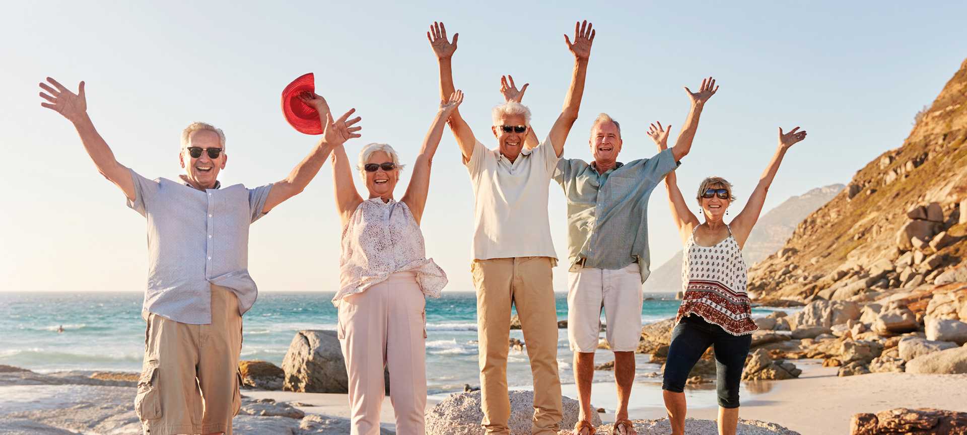 Group of friends with arms outstretched enjoying an escorted tour on the beach