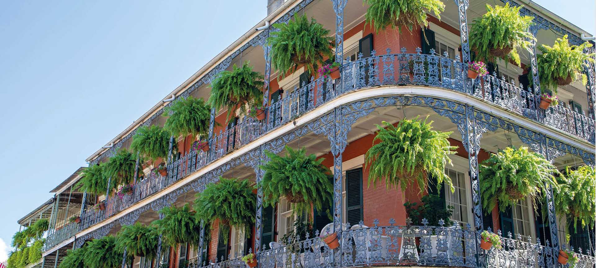 Hanging baskets are displayed on the ornate balconies of a building in the French Quarter of New Orleans