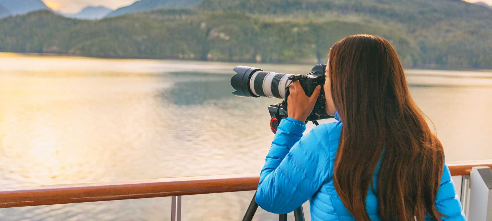 A photographer sets up a tripod to take a photo from the deck of a cruise ship in Alaska
