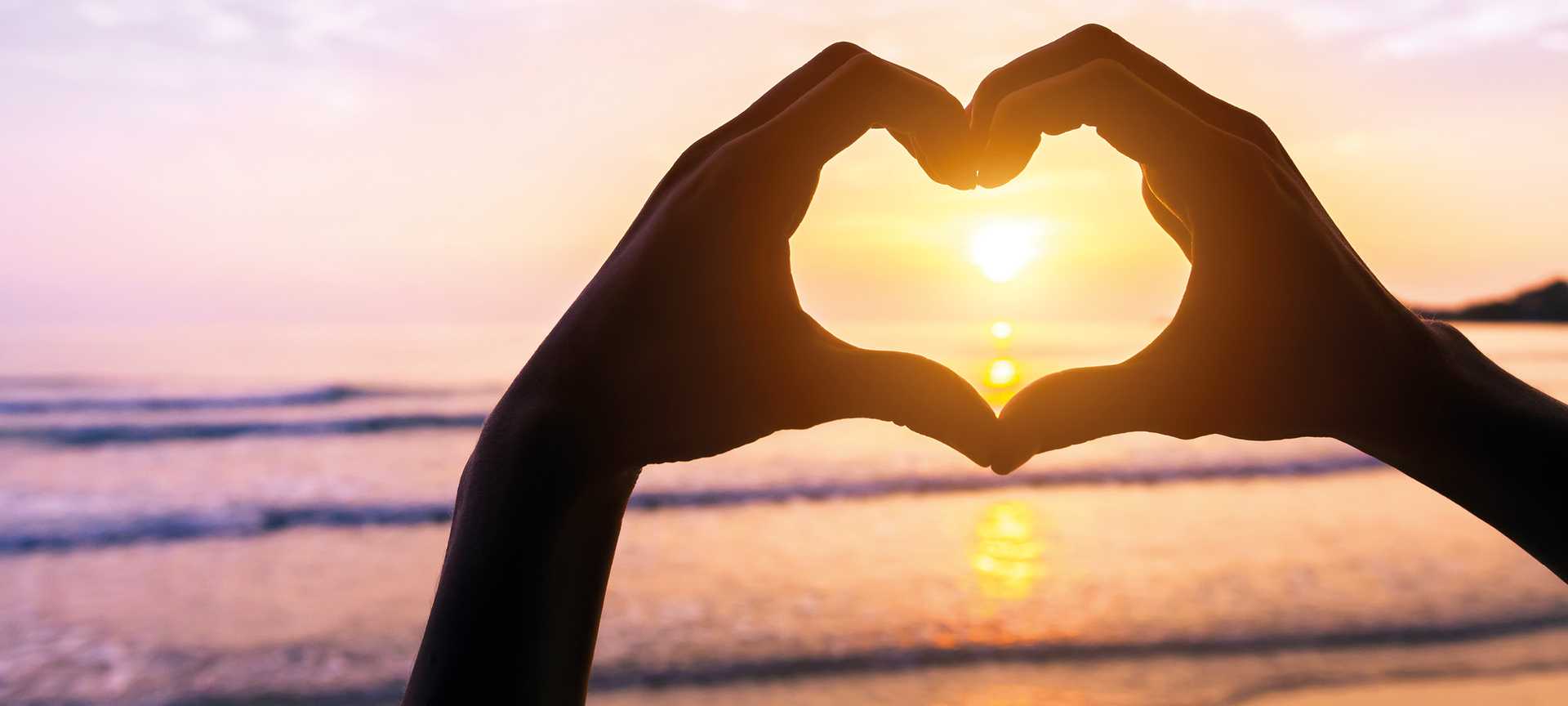 Hands making a heart shape around the sun