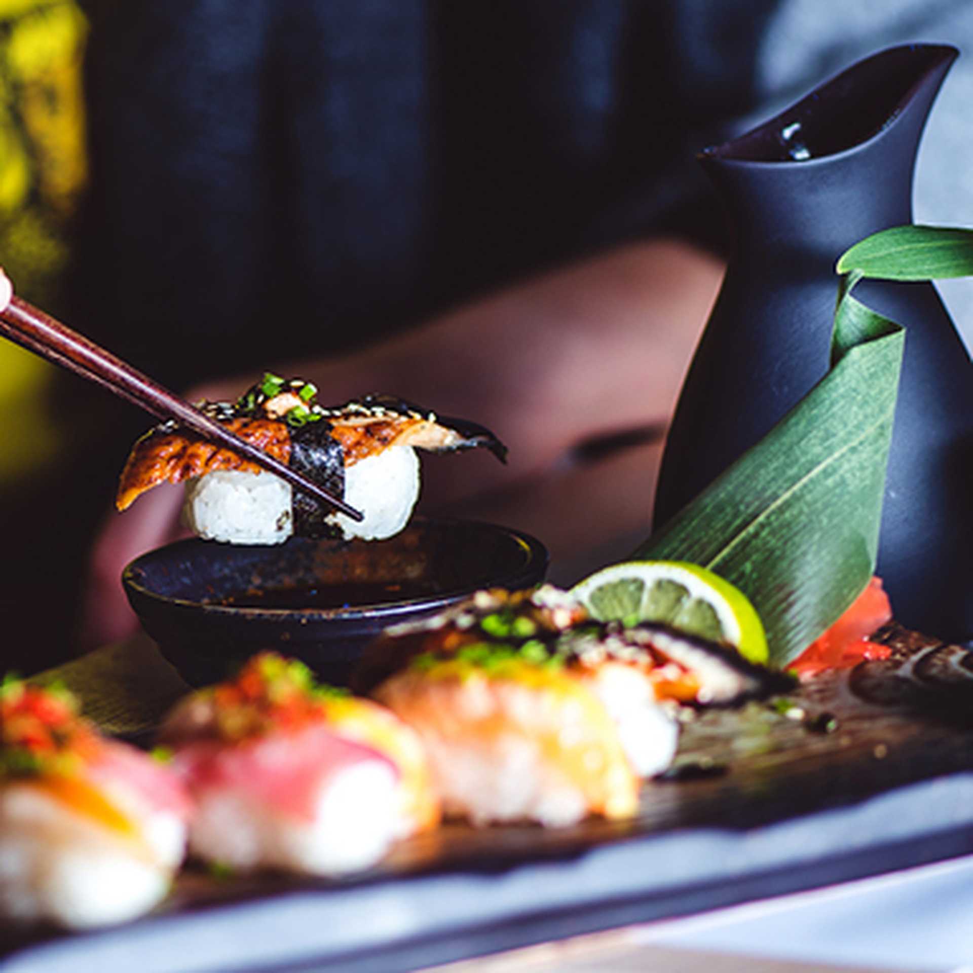 Man eating sushi set with chopsticks on restaurant