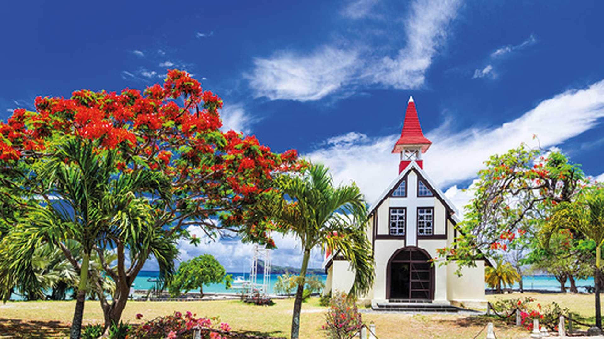 Red church on the beach with blooming flamboyant tree, Cap Malheureux, Mauritius