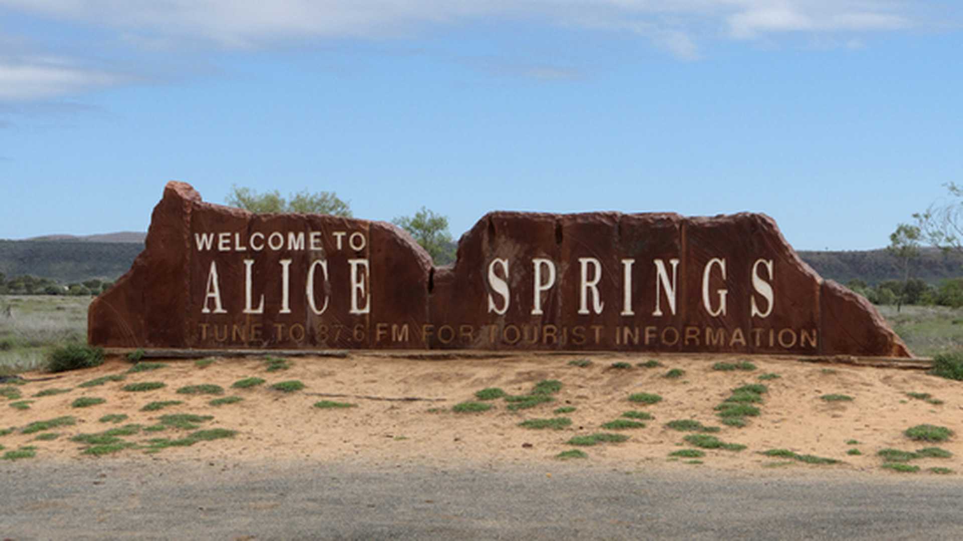 A 'Welcome to Alice Springs' sign stands on the roadside in Australia's Red Centre