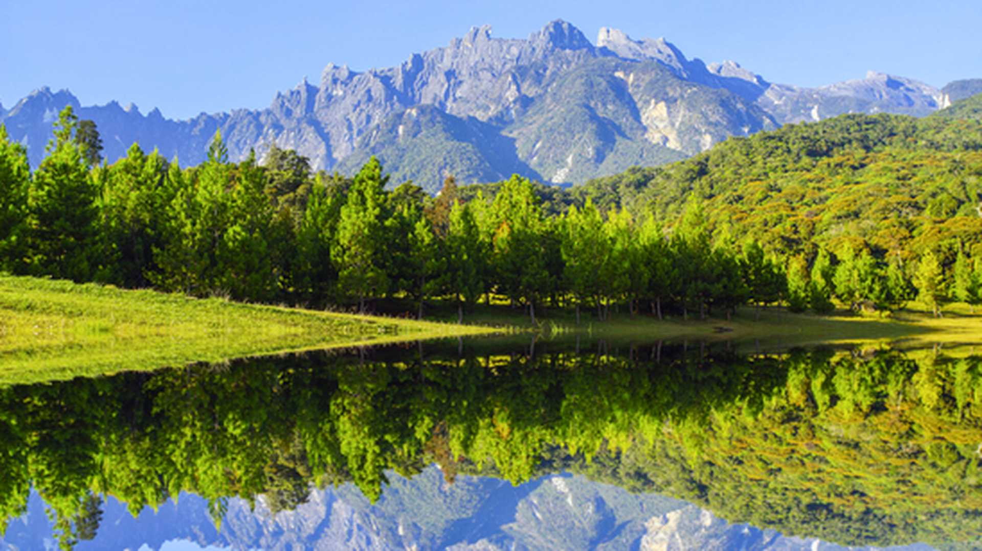 Looking across a lake and forest towards the peak of Mount Kinabalu, Borneo